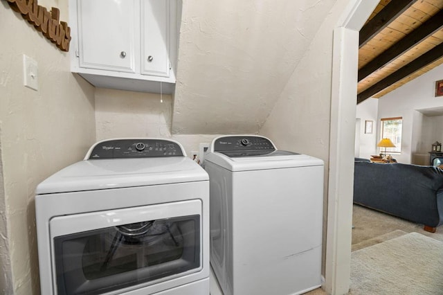 washroom featuring light carpet, washing machine and clothes dryer, wooden ceiling, and cabinets