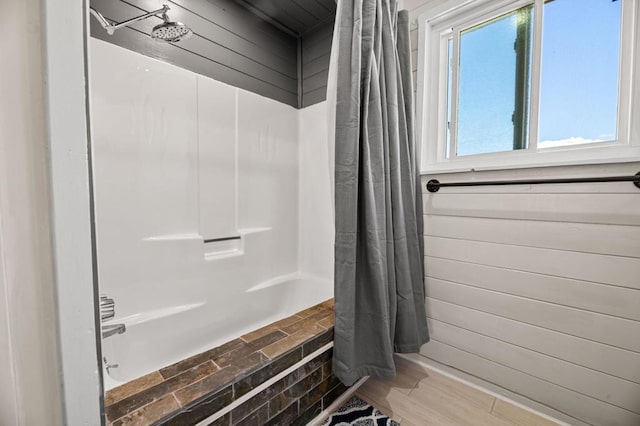 bathroom with hardwood / wood-style flooring and shower / bathtub combination with curtain