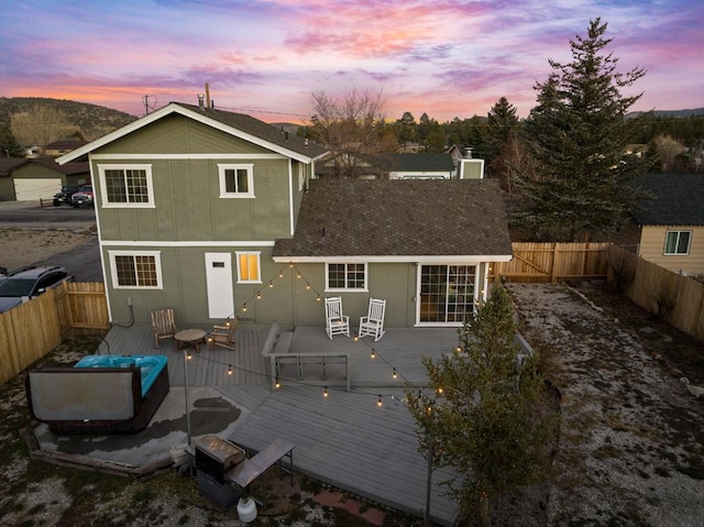 back house at dusk with a wooden deck