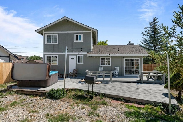 back of property with a hot tub, a deck, and a patio area