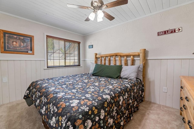 bedroom with wooden walls, wooden ceiling, ornamental molding, carpet flooring, and ceiling fan