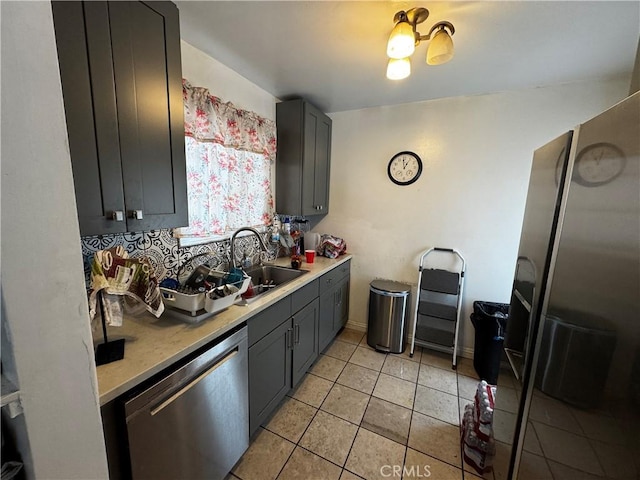 kitchen with light tile patterned flooring, sink, gray cabinetry, tasteful backsplash, and stainless steel dishwasher