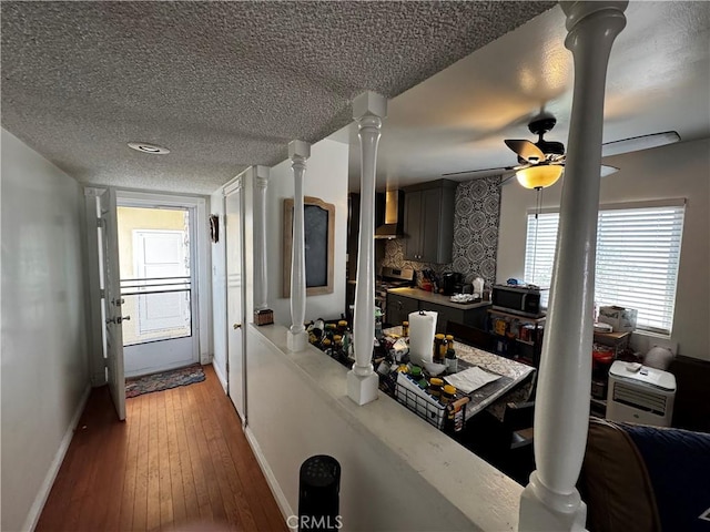 kitchen with ornate columns, tasteful backsplash, a textured ceiling, hardwood / wood-style flooring, and wall chimney range hood