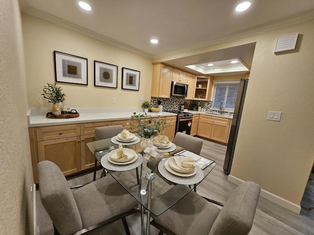 dining space with crown molding, light hardwood / wood-style floors, a raised ceiling, and sink