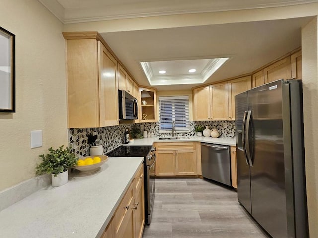 kitchen featuring stainless steel appliances, a raised ceiling, light brown cabinets, crown molding, and sink