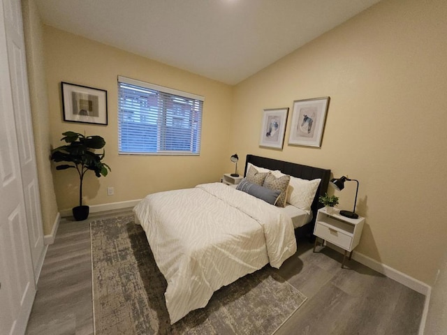 bedroom with dark wood-type flooring and lofted ceiling