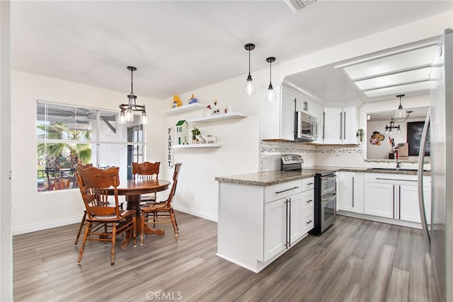 kitchen featuring white cabinets, appliances with stainless steel finishes, hardwood / wood-style flooring, and hanging light fixtures