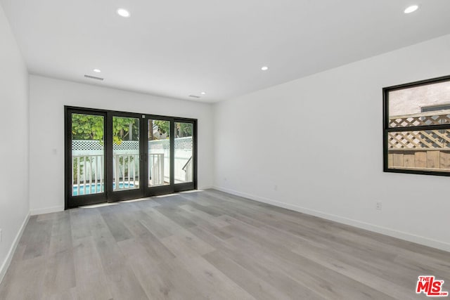 spare room with french doors and light hardwood / wood-style flooring