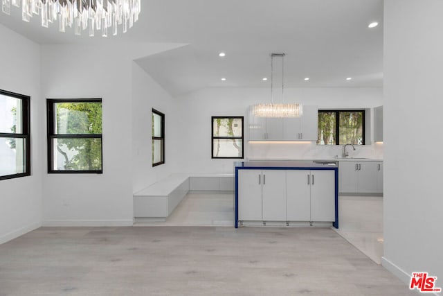 kitchen with sink, decorative light fixtures, light hardwood / wood-style flooring, white cabinets, and a chandelier