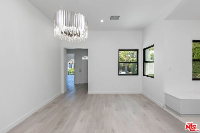 spare room featuring a chandelier and light hardwood / wood-style floors