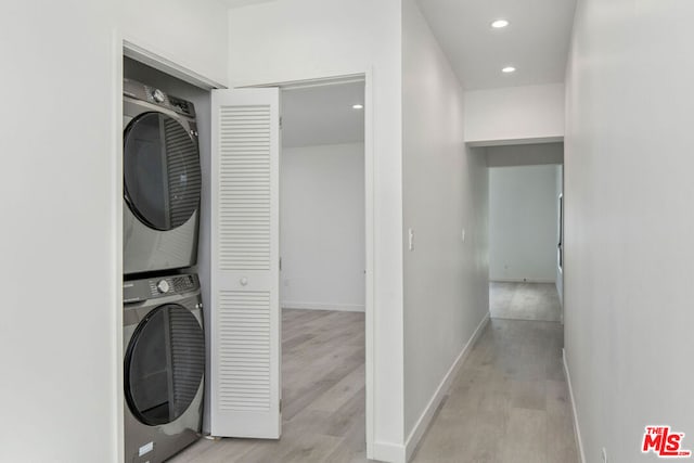 laundry room with light hardwood / wood-style floors and stacked washer and clothes dryer