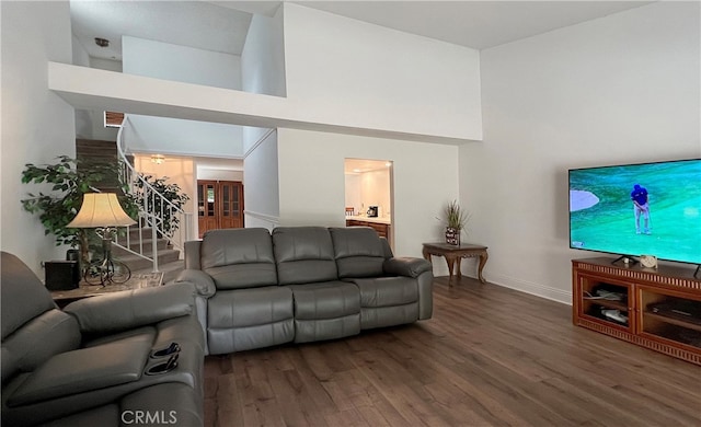 living room featuring dark wood-type flooring and a high ceiling