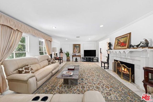 living room featuring a high end fireplace and crown molding