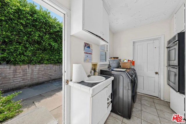 laundry area featuring cabinets, light tile patterned floors, and washing machine and clothes dryer