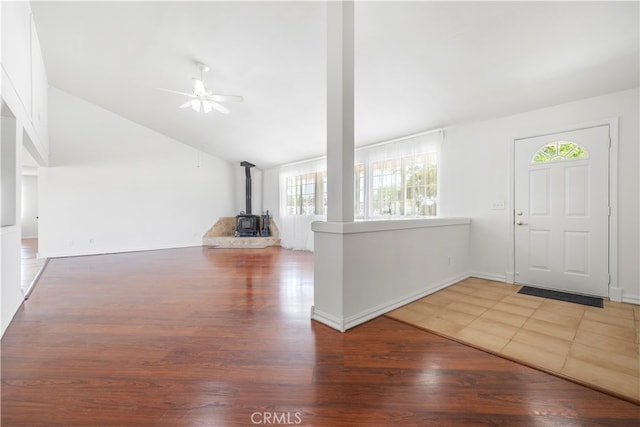 entrance foyer featuring ceiling fan, lofted ceiling, hardwood / wood-style floors, and a wood stove