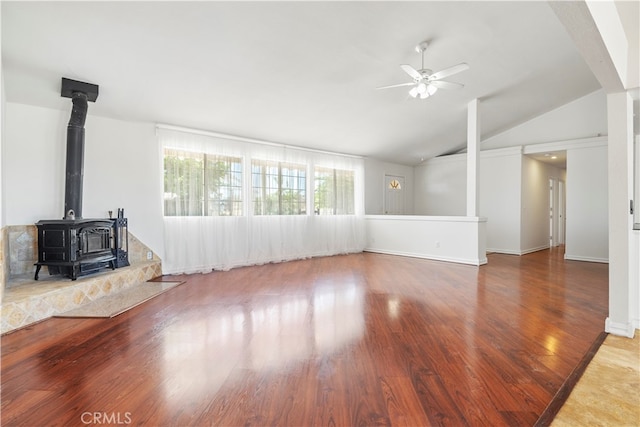 unfurnished living room featuring wood-type flooring, lofted ceiling, ceiling fan, and a wood stove