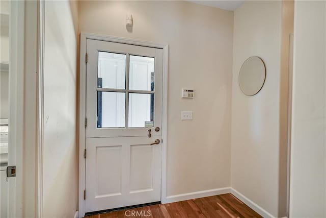 doorway with baseboards and wood finished floors
