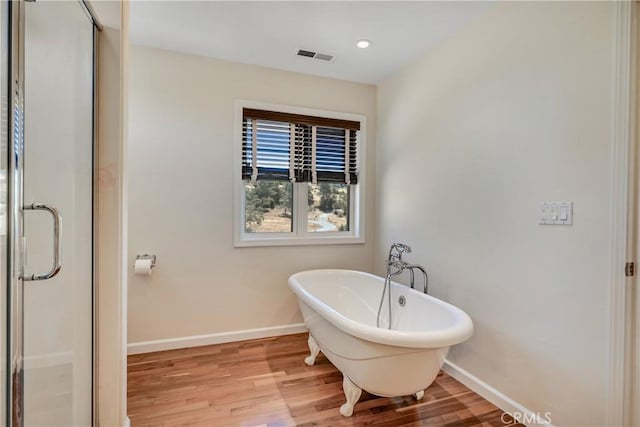 bathroom with wood-type flooring and shower with separate bathtub