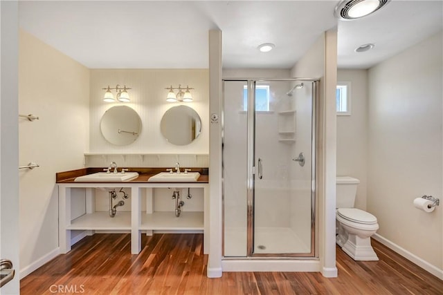 bathroom with hardwood / wood-style flooring, vanity, toilet, and a shower with shower door