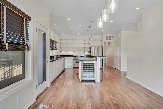 kitchen with dark countertops, open shelves, wine cooler, stainless steel appliances, and light wood-style flooring