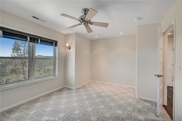 spare room with carpet floors, ceiling fan, visible vents, and baseboards