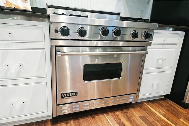interior details featuring designer stove, white cabinetry, and dark wood-type flooring