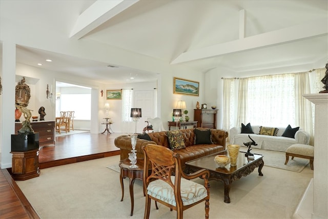 carpeted living room with beamed ceiling, plenty of natural light, and high vaulted ceiling