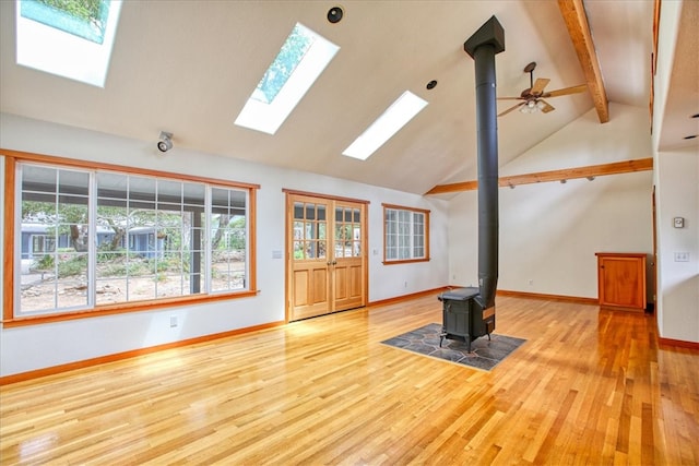 unfurnished living room featuring light wood-type flooring, high vaulted ceiling, beamed ceiling, and a wood stove