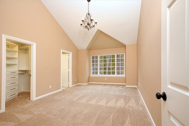 unfurnished bedroom featuring an inviting chandelier, high vaulted ceiling, a spacious closet, and light colored carpet