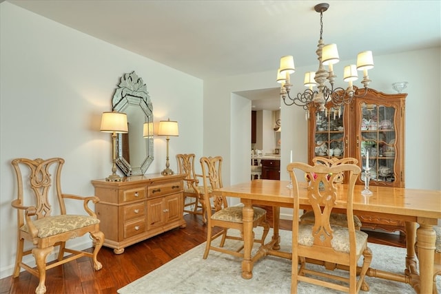 dining area with a notable chandelier and dark hardwood / wood-style flooring