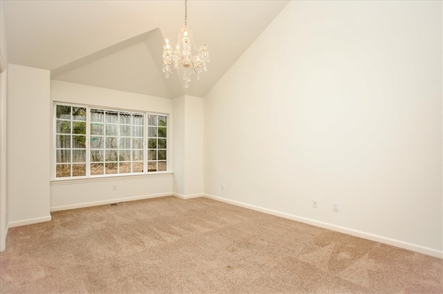 empty room featuring lofted ceiling, carpet floors, and a chandelier