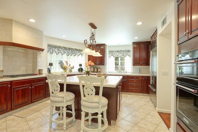 kitchen featuring a breakfast bar, stainless steel appliances, a center island, decorative backsplash, and decorative light fixtures