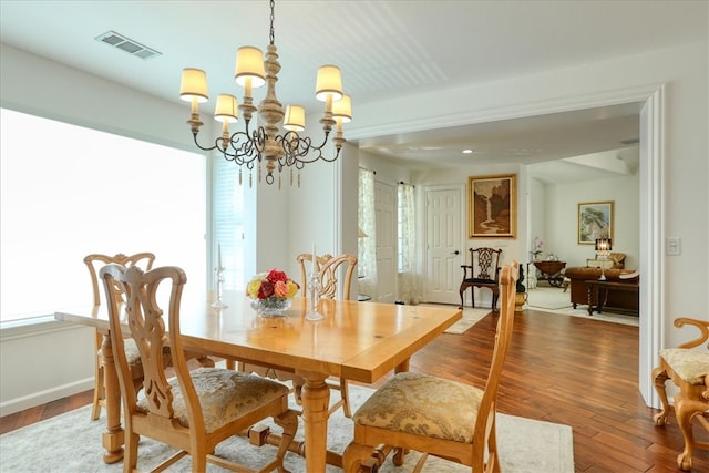 dining area featuring dark hardwood / wood-style flooring and an inviting chandelier