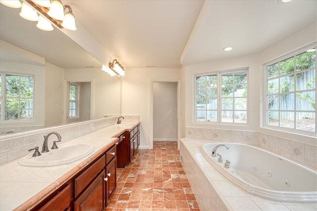 bathroom featuring vanity, a relaxing tiled tub, and a notable chandelier