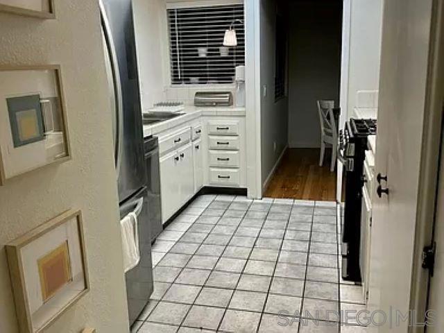 kitchen with white cabinetry, gas stove, and light tile patterned flooring