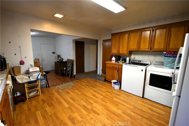 kitchen featuring light wood-type flooring, independent washer and dryer, and white fridge