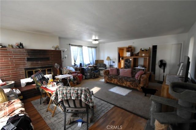 living room with a brick fireplace and hardwood / wood-style flooring