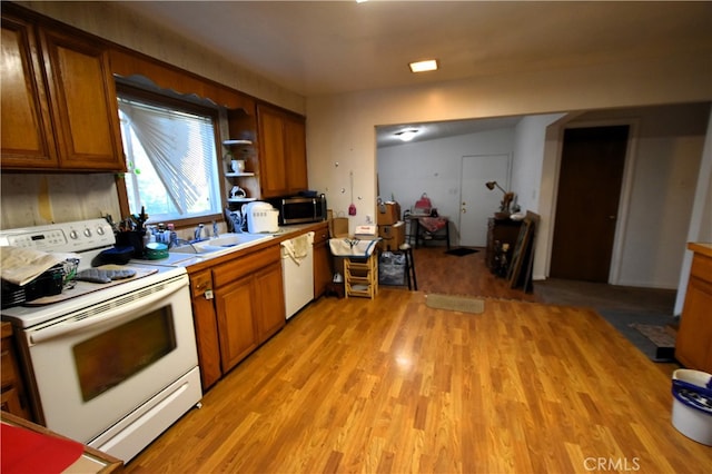 kitchen with light wood-type flooring, white appliances, and sink