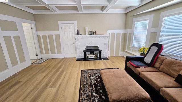 living room featuring a fireplace, coffered ceiling, light hardwood / wood-style flooring, and beamed ceiling