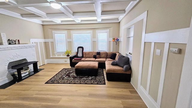 living room featuring beam ceiling, coffered ceiling, a brick fireplace, hardwood / wood-style floors, and ceiling fan