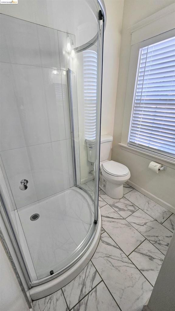 bathroom with a shower with shower door and toilet