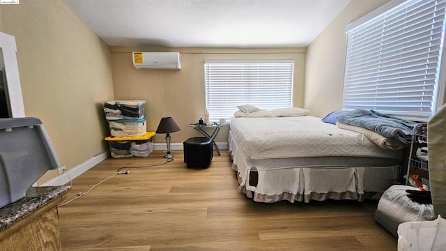 bedroom with light hardwood / wood-style floors and a wall unit AC