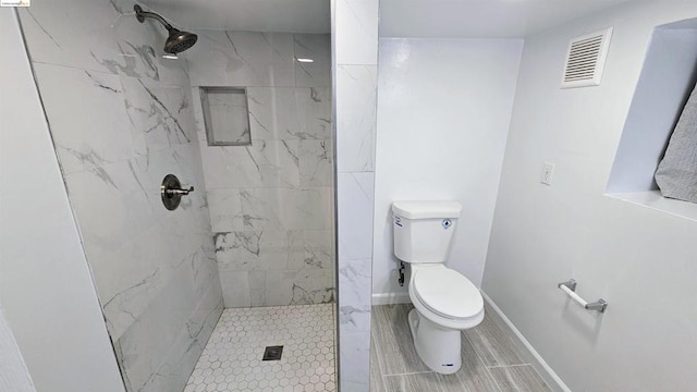 bathroom featuring a tile shower and toilet