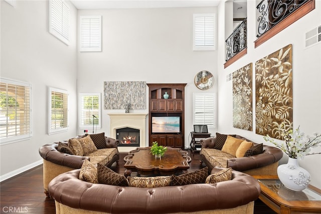 living room with a towering ceiling and dark hardwood / wood-style floors