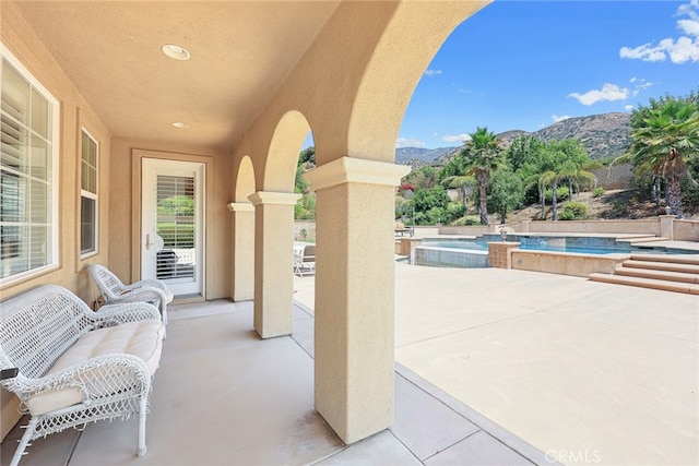 view of patio / terrace featuring a mountain view and a swimming pool with hot tub