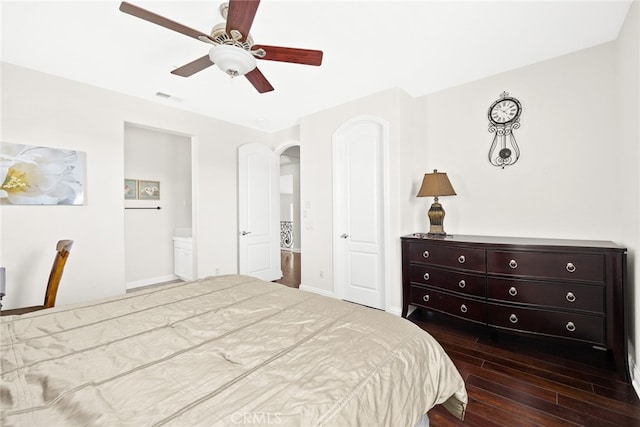 bedroom featuring ceiling fan, ensuite bath, and dark hardwood / wood-style flooring