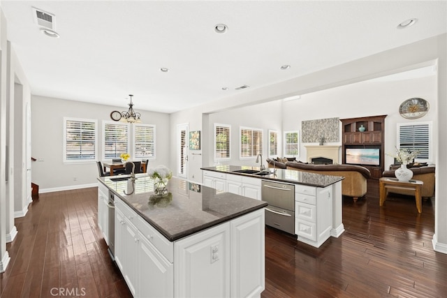 kitchen with a healthy amount of sunlight, a center island with sink, dark hardwood / wood-style flooring, and white cabinets