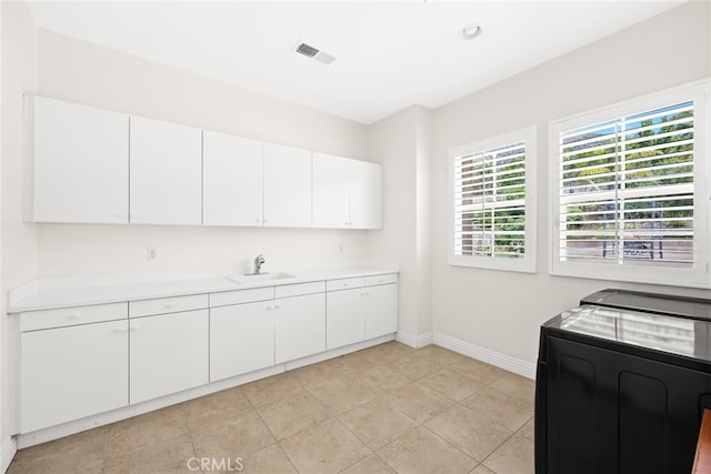 kitchen featuring separate washer and dryer, light tile patterned flooring, sink, and white cabinets