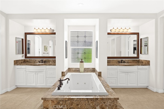 bathroom with tiled tub, vanity, and tile patterned flooring