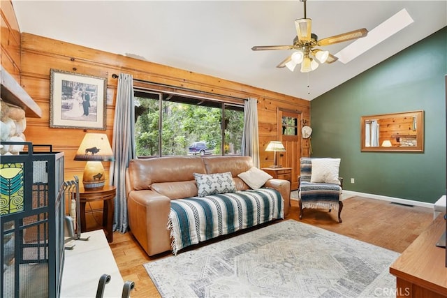 sitting room featuring wood walls, ceiling fan, vaulted ceiling, and light hardwood / wood-style flooring